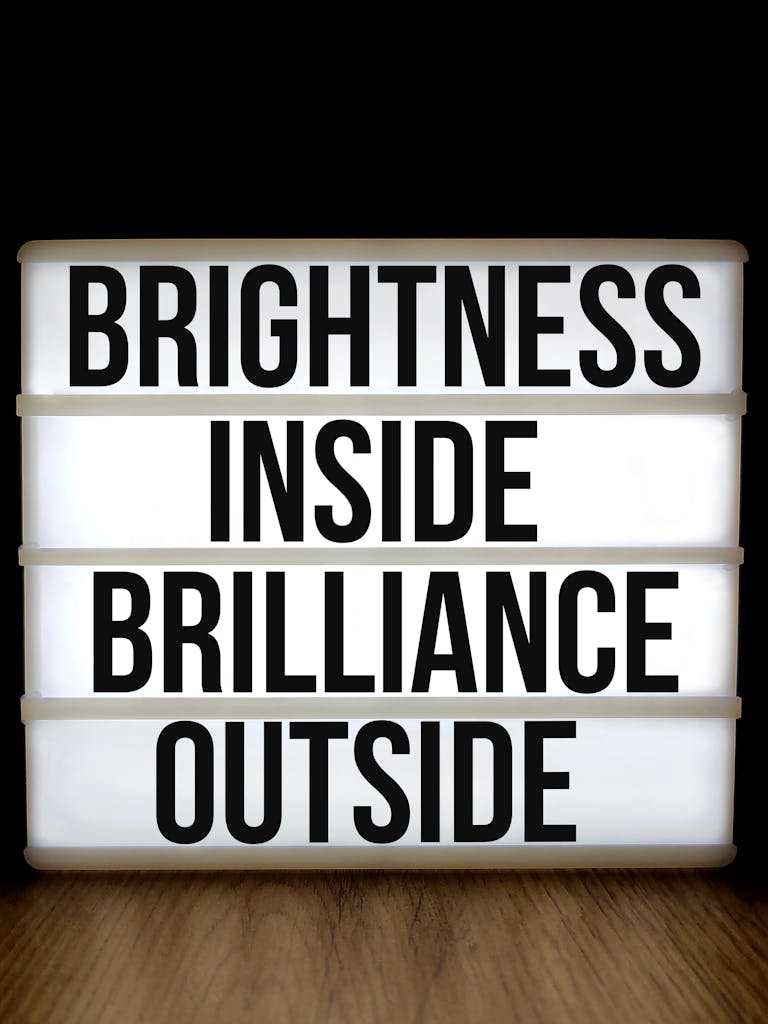 Lightbox sign with motivational message 'Brightness Inside Brilliance Outside' on a woodgrain background.